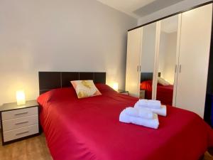 Casa Los Palmeros Perdomo في Alojera: غرفة نوم بسرير احمر عليه مناشف