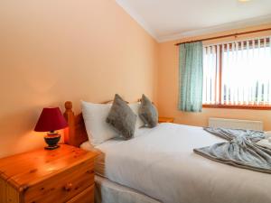 a bedroom with a bed and a table with a lamp at 48 Edenbank Road in Cupar