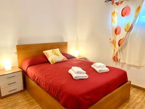 Un dormitorio con una cama roja con toallas. en Casa Los Palmeros Perdomo, en Alojera