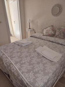 um quarto com uma cama com lençóis brancos e almofadas em Casedda Ostunese em Ostuni