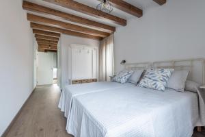a white bedroom with a white bed with blue pillows at Casa de Miranda in Ézaro