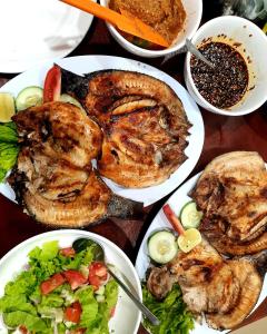 a table topped with plates of food and bowls of salad at Juma cottages in Tuk Tuk