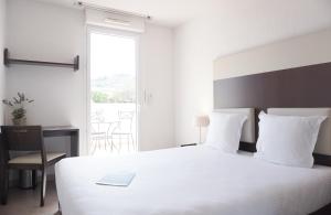 シス・フール・レ・プラージュにあるZenitude Hôtel-Résidences Toulon Six Foursのベッドルーム1室(白いベッド1台、デスク、窓付)