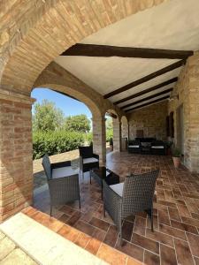 un patio al aire libre con mesas, sillas y una pared de ladrillo en Agriturismo Il Gonzeto, Montepulciano, en Montepulciano