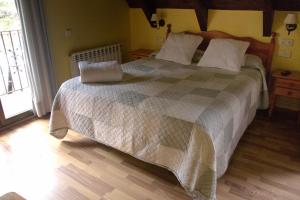 a bedroom with a large bed with a checkered blanket at Hotel Saueth in Tredós