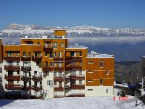 a building in the snow with a mountain in the background at Studio central avec balcon et vues sur pistes - 3 couchages - FR-1-557-44 in Les Adrets