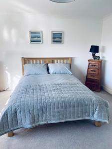 a bed with a blue comforter and a dresser in a bedroom at Driftwood Lodge in Llansantffraid Glan Conwy