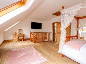 a bedroom with a canopy bed and a television at Little Lodge in Kings Lynn