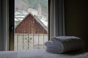a room with a bed and a window with a barn at Hotel Saueth in Tredós