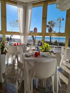 un comedor con mesas y sillas blancas y el océano en Rifugio dei Saraceni, en Vallecrosia