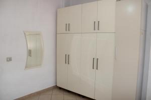 Armario blanco con espejo y armarios blancos en Bledi's Comfy Apartment in New Blvd / Free Parking, en Tirana