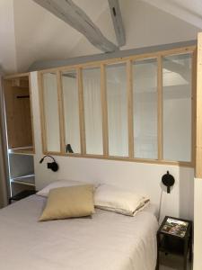 a bedroom with a white bed with glass windows at La Maison du Cocher - Chambre indépendante climatisée en Hypercentre - Lit Queen Size in Angers