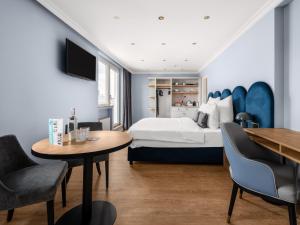 デュッセルドルフにあるnuma I Artol Rooms & Apartmentsのベッド、テーブル、椅子が備わるホテルルームです。