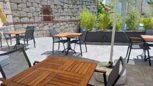 un patio con mesas y sillas y una pared de piedra. en Hotel Doğa Çeşme, en Cesme