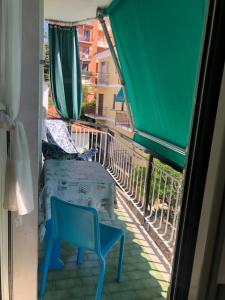 een balkon met een stoel, een tafel en een groene parasol bij Giusy near the sea in Sanremo