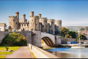 a castle on a bridge over a body of water at Cosy 2 bed terraced house in Conwy in Conwy