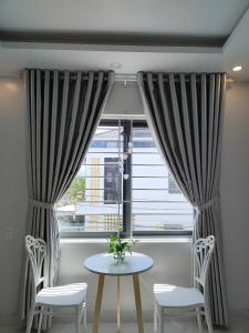 une table et deux chaises devant une fenêtre dans l'établissement Huế Thơ Homestay, à Hue