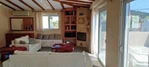 sala de estar con muebles blancos y ventana grande en KimonVilla, en Porto Rafti