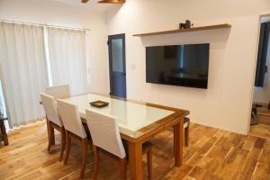 a dining room table with chairs and a television on a wall at Doublerainbow Resort Katsuura in Katsuura