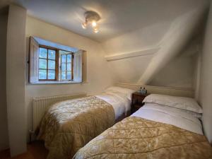 two beds in a room with a window at Baker's Cottage in Castle Combe