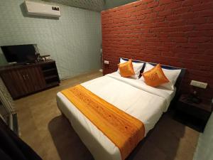 1 dormitorio con 1 cama grande y pared de ladrillo rojo en Tamboo Resort Vajreshwari, en Thane