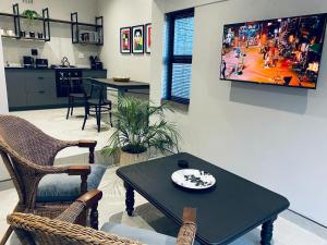 ein Wohnzimmer mit einem Tisch und einem TV an der Wand in der Unterkunft 46 on Allcock Guest Apartment & Luxury Room in Pretoria