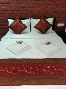 1 cama con sábanas y almohadas blancas y pared de ladrillo en Tamboo Resort Vajreshwari en Thane