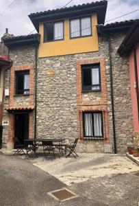 een gebouw met een tafel en stoelen ervoor bij ApartamentosArturo CasaRural Pancarale-Llanes in Llanes