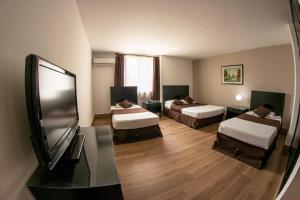 a hotel room with two beds and a flat screen tv at Hotel Americana in Cali