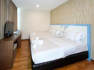 ein Schlafzimmer mit einem großen weißen Bett und einem TV in der Unterkunft MII Smile Hotel Penang in George Town