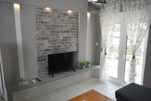 a living room with a brick wall and a flat screen tv at VIRGIN ROCKS APARTMENTS 1 in Kalabaka