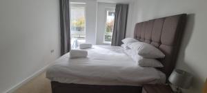 Bett in einem Zimmer mit einem großen Fenster in der Unterkunft Empress at College - Spacious 2 bedroom apartment in Southampton