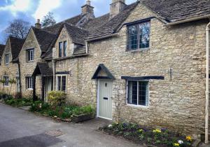 an old stone house with a white door at Baker's Cottage in Castle Combe