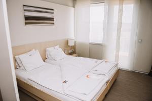a large white bed in a room with a window at Wabi Hotel - Beauty & Dental Center in Sopron