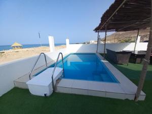 a swimming pool on the side of a house next to the beach at Wadi shab guest house in Ţīwī