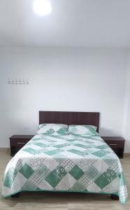 1 dormitorio con 1 cama con edredón verde y blanco en HOSTAL PARIS, en Manta