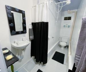 a bathroom with a black shower curtain and a sink at Tiny House in Pipa