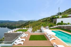 um resort com piscina e espreguiçadeiras em Delfim Douro Hotel em Lamego