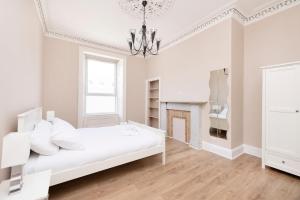 um quarto branco com uma cama branca e uma lareira em ALTIDO Cosy 3bed Family flat near Leith em Edinburgo