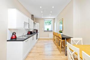 een keuken met witte kasten en een tafel en stoelen bij ALTIDO Cosy 3bed Family flat near Leith in Edinburgh