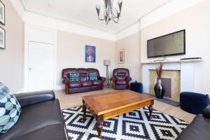 een woonkamer met lederen meubels en een open haard bij ALTIDO Cosy 3bed Family flat near Leith in Edinburgh