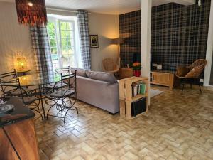 a living room with a couch and a table and chairs at La Maison des Tilleuls in Saint-Germain-sur-Sèves