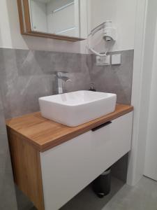 a white sink on a wooden counter in a bathroom at Domek na Kępie in Sromowce Wyżne
