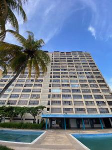 a large building with a palm tree in front of it at Ocean View. Acogedor Apartamento frente al mar in Porlamar