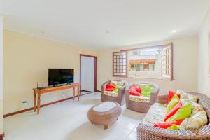 sala de estar con sillas de mimbre y TV en GB09 Ótima Casa 6 Quartos a 50m da Praia, en Guarajuba