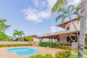 una casa con una piscina y una palmera en GB09 Ótima Casa 6 Quartos a 50m da Praia, en Guarajuba