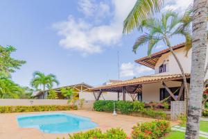 a house with a swimming pool and a palm tree at GB09 Ótima Casa 6 Quartos a 50m da Praia in Guarajuba