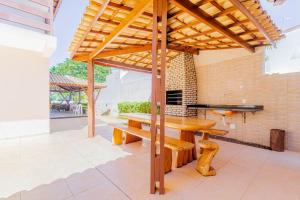 a wooden table and bench under a wooden pergola at GB09 Ótima Casa 6 Quartos a 50m da Praia in Guarajuba
