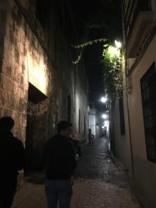 a man walking down an alley at night at Patio de la Plateria in Córdoba