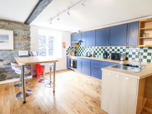 Harbour Suite في بورثمادوج: مطبخ مع دواليب زرقاء وارضية خشبية